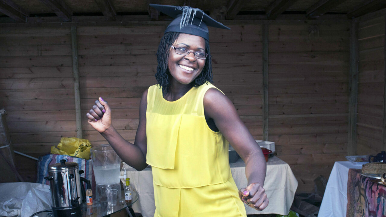 One of Glenn Edwards' portrait photos featuring an African woman celebrating her graduation wearing a yellow dress and mortar board hat