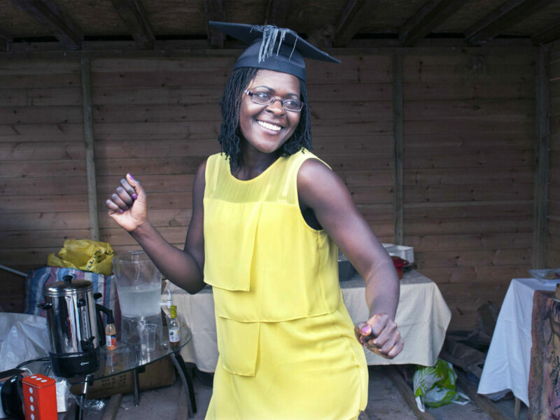 One of Glenn Edwards' portrait photos featuring an African woman celebrating her graduation wearing a yellow dress and mortar board hat