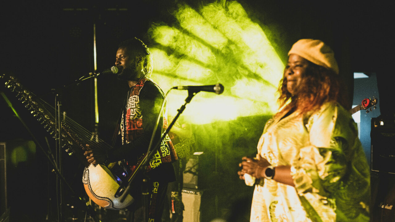 Suntou Susso singing into microphone with Binta Susso standing away from her microphone