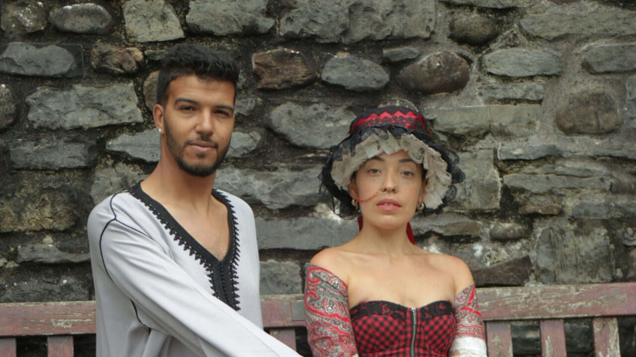 Ayoub & Ffion in traditional Moroccan & Welsh attire, sitting down